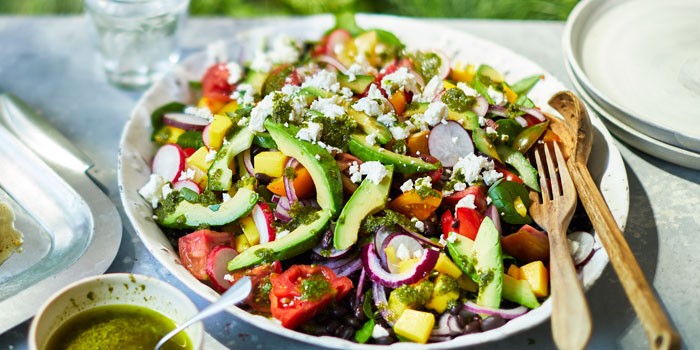 Large summer salad on a plate, topped with feta