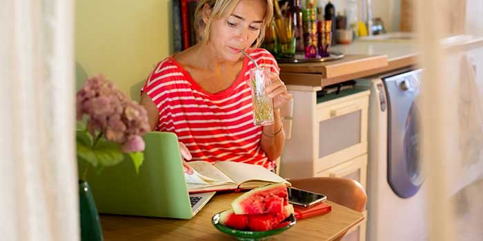 A woman drinking in front of a laptop