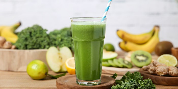 Green smoothie surrounded by ingredients