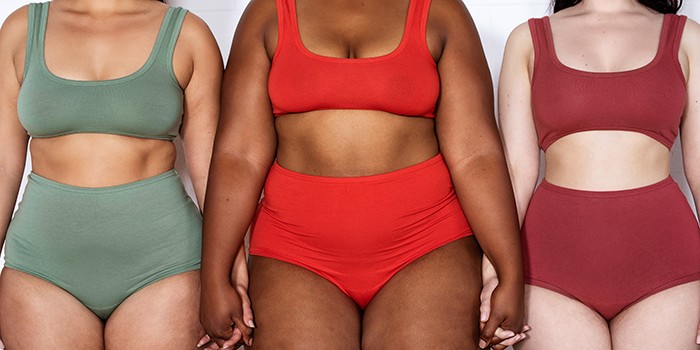 Several women holding hands in a line with different body shapes