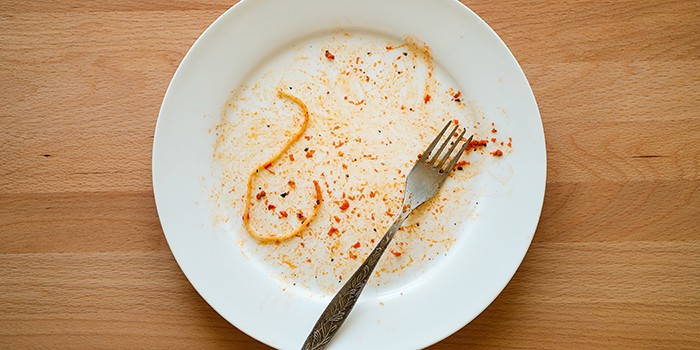 Empty plate with a single strand of spaghetti left