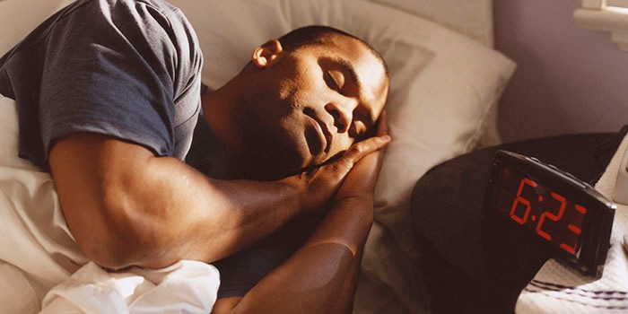 Man sleeping in bed with a digital alarm