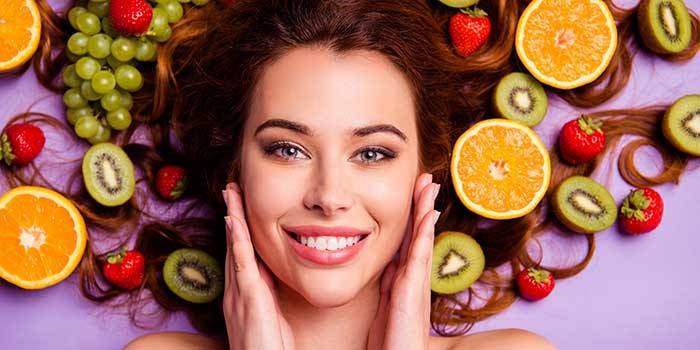 A woman lying down with fruit surrounding her to denote skin health