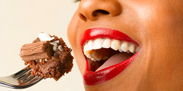 Smiling mouth about to eat a forkful of chocolate cake