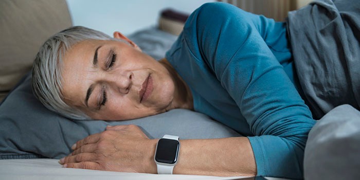 Woman asleep and using sleep tracker