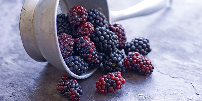 Small zinc container with fresh blackberries spilling out