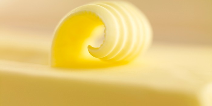 Extreme close-up of a block of butter, with a scraped curl on top