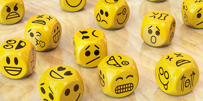 Lots of yellow dice with a different emotion illustrated on each side with a cartoon face