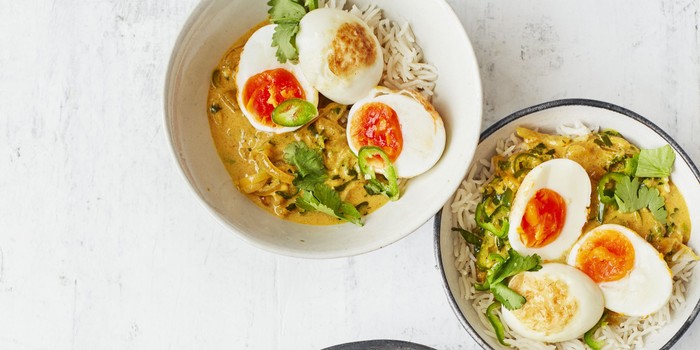 Masala curry and rice in a white bowl topped with boiled eggs