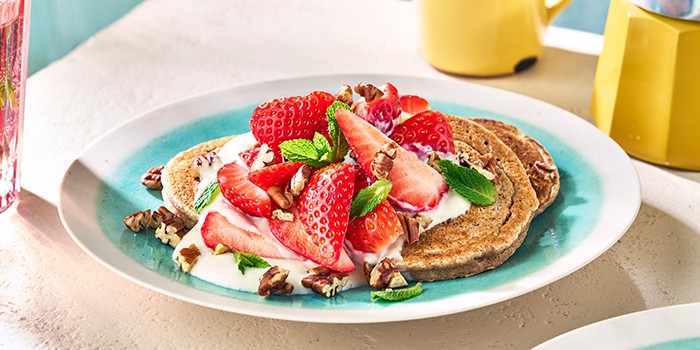 Vegan strawberry pancakes with yogurt, pecans and fresh mint