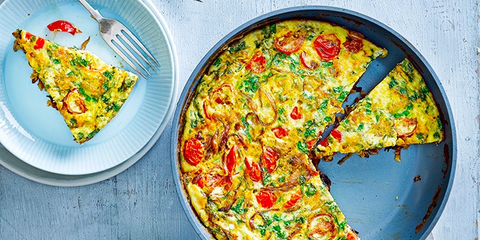 Masala frittata in a frying pan with a slice taken