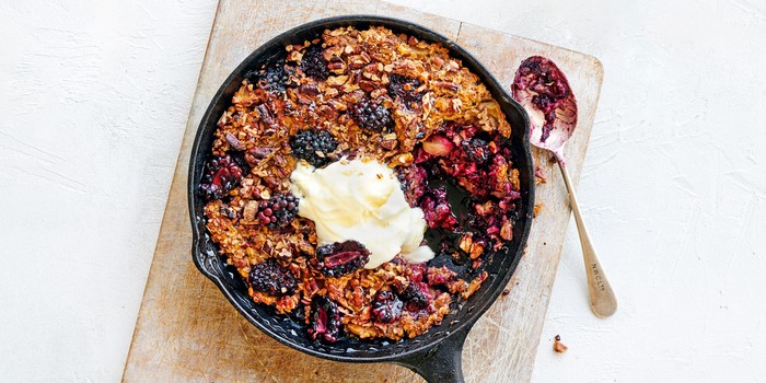 Blackberry and apple oat bake in a round skillet pan with spoon