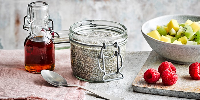 A pot of chia pudding with syrup and fresh fruit