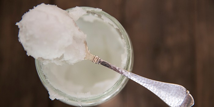 Overhead view of spoonful of cold coconut oil on jar