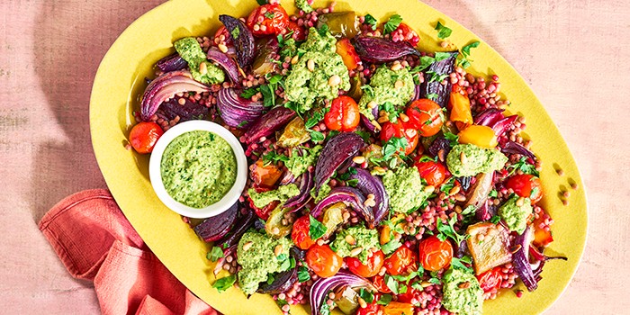 Giant couscous salad with charred veg & tangy pesto on a yellow plate