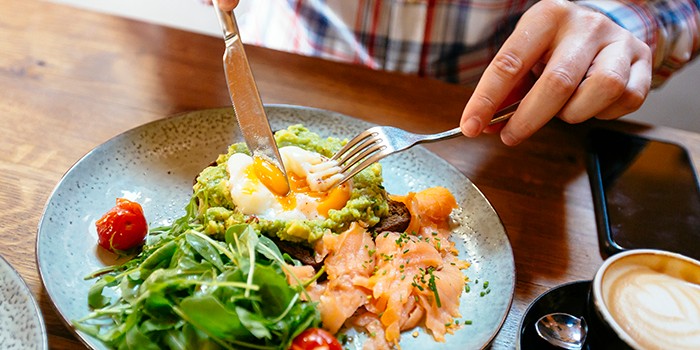 Man eating avocado toast with egg and smoked salmon