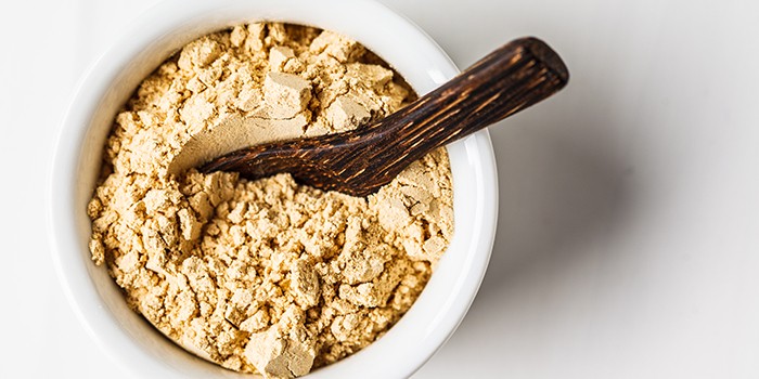 Superfood maca powder in a white bowl on a white background