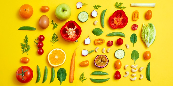 Selection of raw foods laid out on yellow background