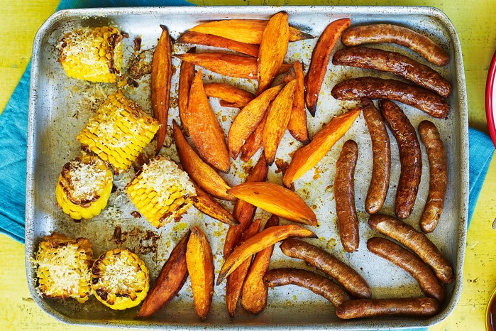 Tray of corn on the cob, sweet potato wedges and sausages