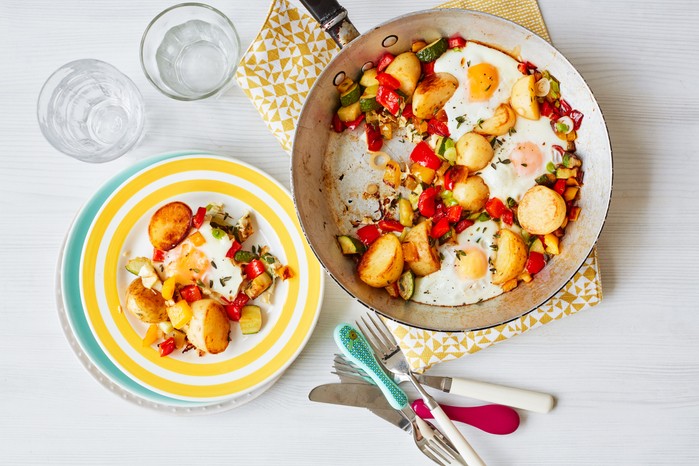 A pan of veg topped with eggs, plus a serving on a plate next to it