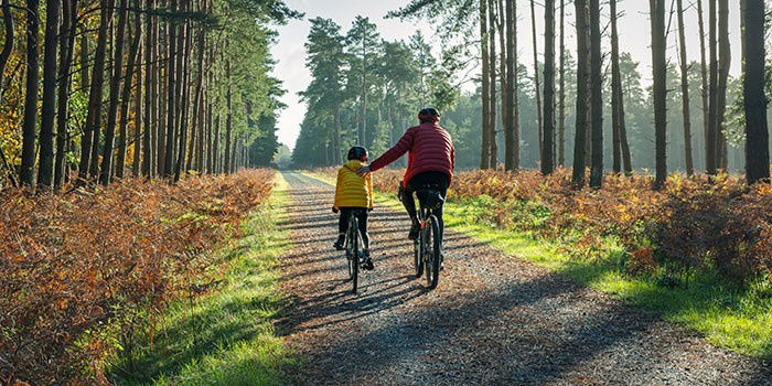 A child and adult riding bikes through a forest