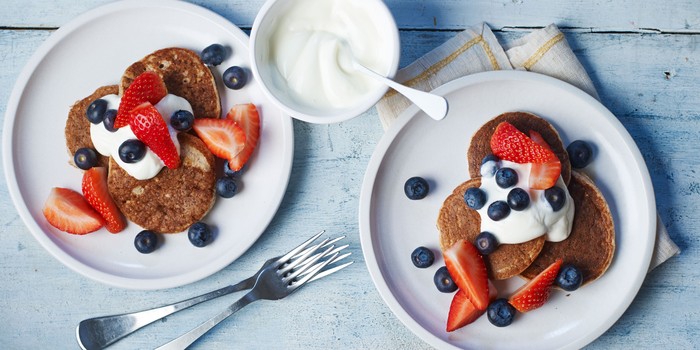 Two plates of pancakes topped with yoghurt and fruit