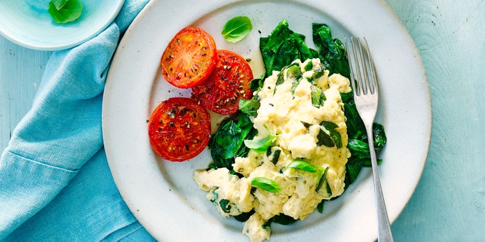 Scrambled eggs with tomatoes and spinach on a plate