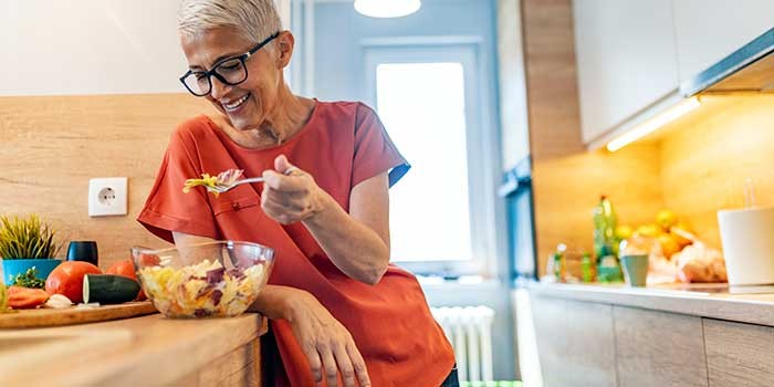 An older woman preparing a salad
