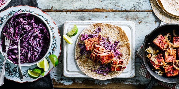 Curried tofu wraps on a board with shredded cabbage and fresh lime