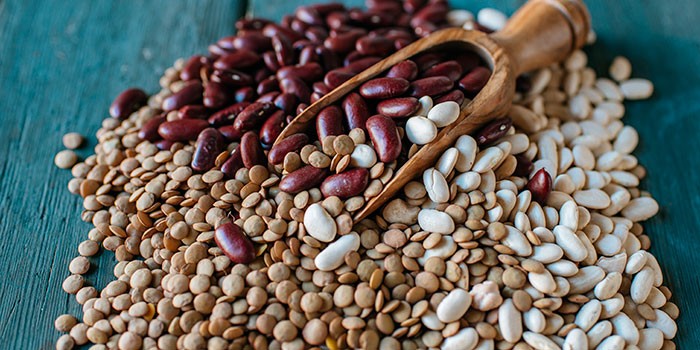 Pile of dried beans with scoop on blue table