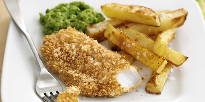 Crispy fish & chips with mushy peas on a white plate