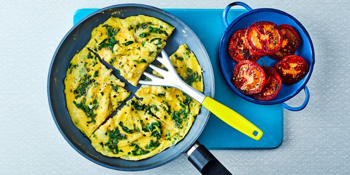 Herb omelette in a frying pan with tomatoes