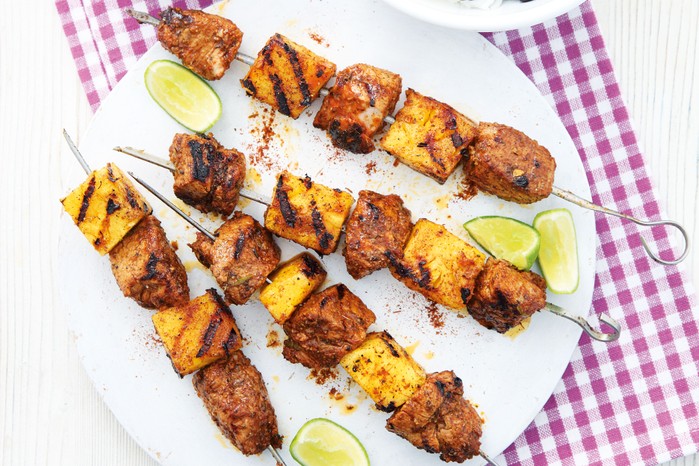 Skewers of pork and pineapple with lime wedges