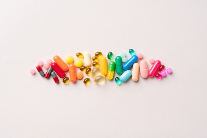 A group of brightly coloured pills and capsules on a pale background