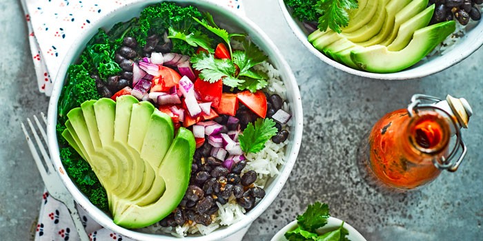 Burrito bowl with chipotle black beans, sliced avocado, rice and hot sauce