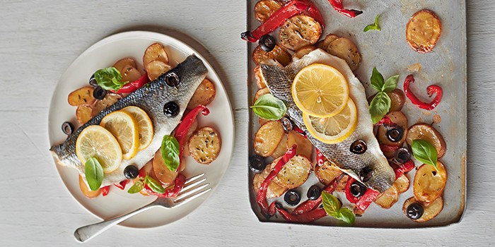 Roast veg and sea bass on a plate and baking tray
