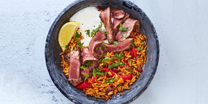 Steak burrito bowl with rice, peppers and lemon