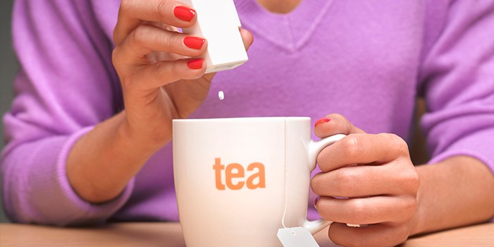 Artificial sweetener tablet falling from a dispenser into a mug of tea
