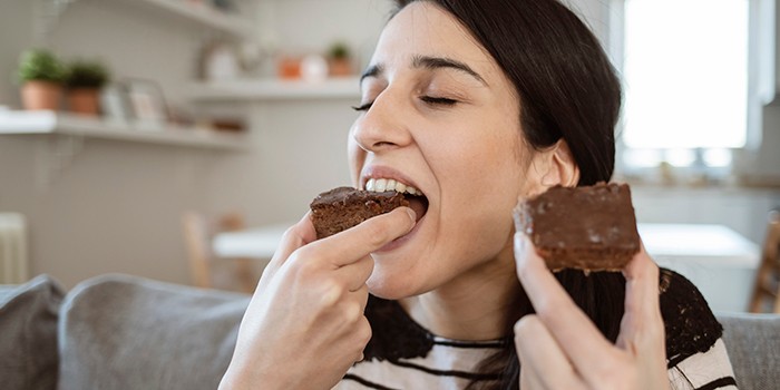 Woman enjoying pieces of chocolate brownie