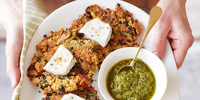 Kale and quinoa patties on plate with a bowl of pesto