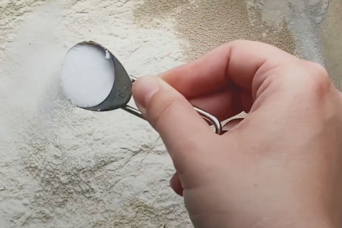 Hand sprinkling salt into flour and yeast